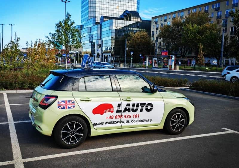 Suzuki Swift OSK Lauto z tablicą L na parkingu przy ul. Ogrodowej 5 w Warszawie — auto szkoleniowe kat. B